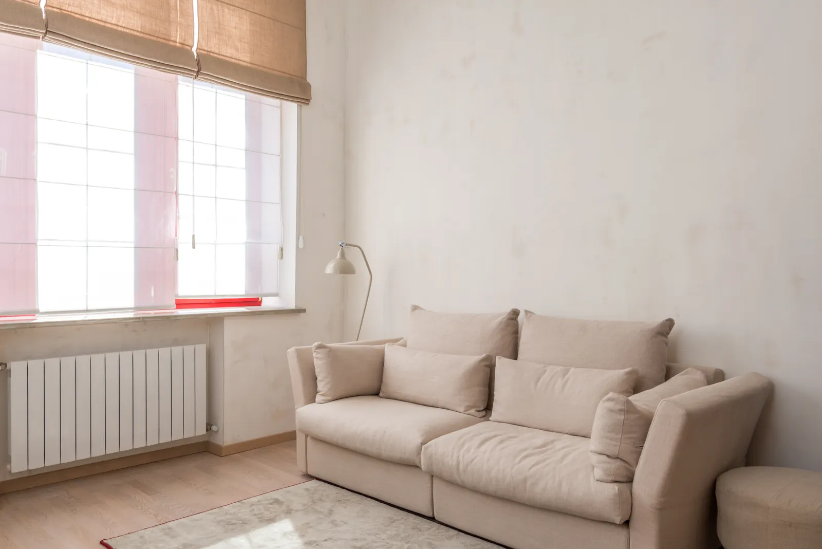 Heller, minimalistisch eingerichteter Wohnraum mit hellem Sofa und Tageslicht