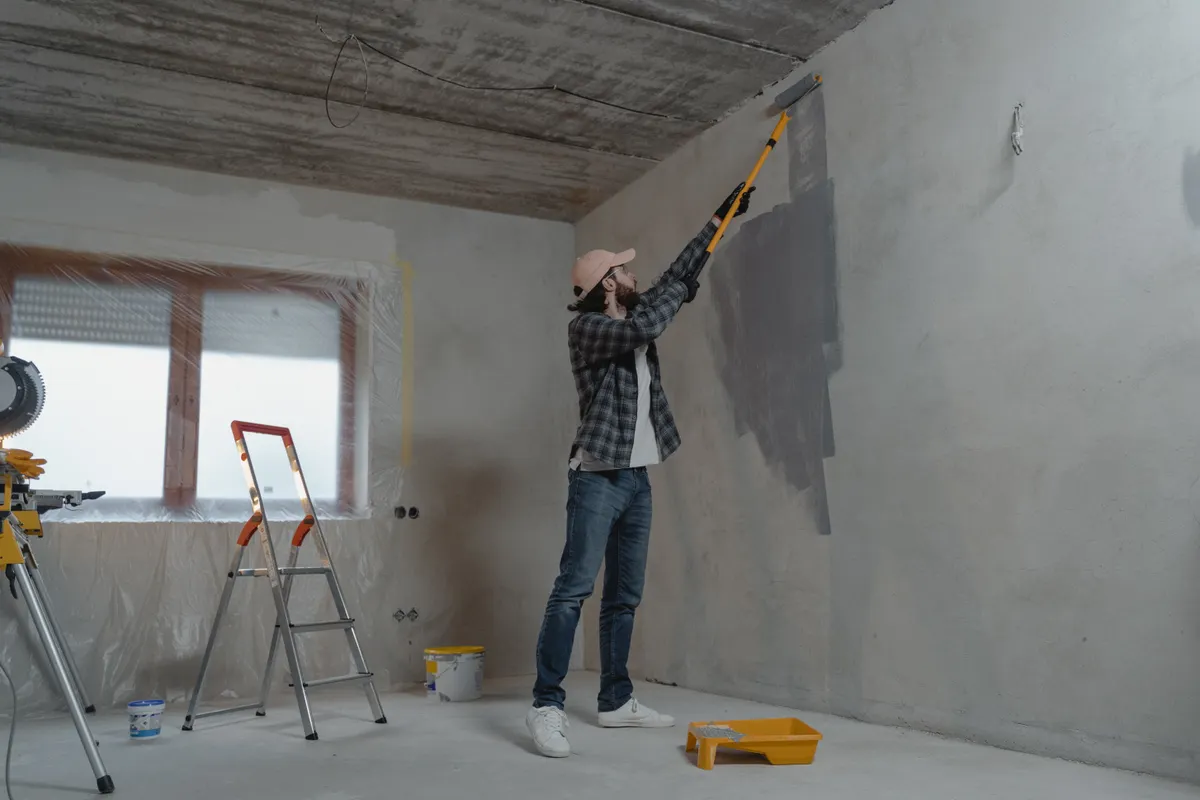 Handwerker streicht eine Innenwand mit der Rolle während der Renovierung